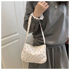 Detail of a ruffled fabric hobo bag featuring pink bow patterns and a shoulder strap