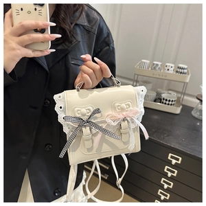 Detail of white lace handbag featuring decorative bows and cute character charms