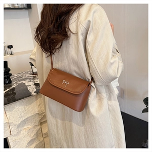 Detail of caramel brown matte leather crossbody bag with silver bow buckle