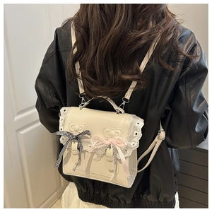 Detail of cream white Lolita backpack with lace trim and bow on a leather jacket