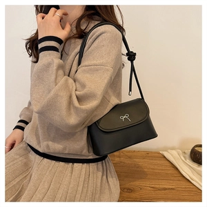 Détail du sac à bandoulière en similicuir noir avec nœud argenté élégant et chic