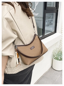 Detail of brown canvas hobo bag with wood bead tassel and leather trim detailing