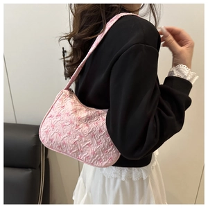 Detail view of pink bow-embossed shoulder bag worn by a model in a minimalist setting