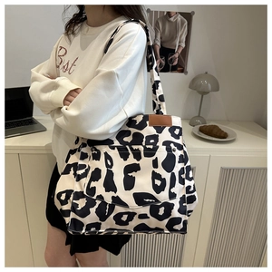 Detail of leopard print canvas tote bag with brown leather accent and front pocket