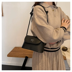 Détail d'un sac bandoulière noir chic avec nœud argenté et design de bandoulière nouée