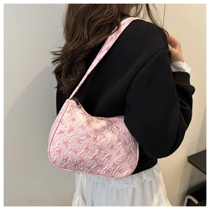 Pink shoulder bag with bow prints and pleated texture shown on a female model