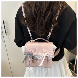 Detail of pink PU leather backpack with lace trim and bows on a black blazer