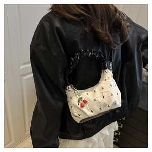 Dettaglio della borsa jacquard bianca con ricamo e ciondolo a forma di ciliegia decorativo