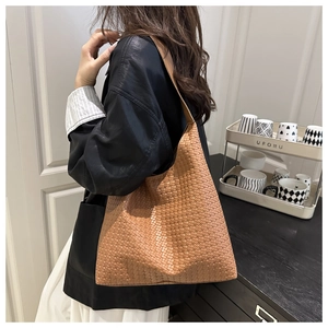 Detailed close-up of the vintage brown woven tote bag carried by a model in a cozy room