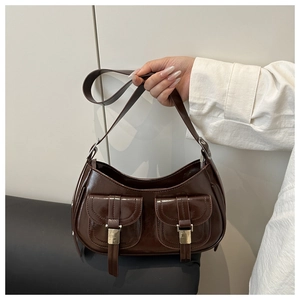 Detail of dark brown faux leather underarm bag with silver buckles and double front pockets