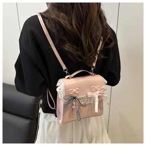 Detail of pink PU leather backpack with delicate white lace embroidery and ribbon bows