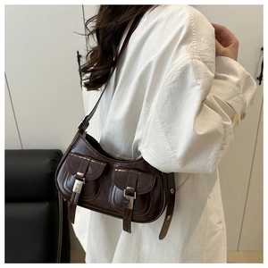 Detail view of dark brown glossy leather shoulder bag with retro utility pockets and silver buckles