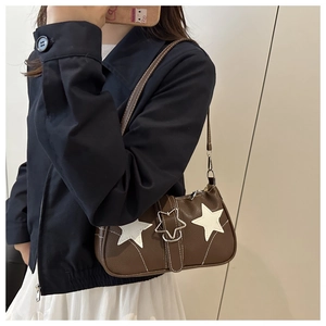 Close-up of a brown leather shoulder bag with white star appliques and metal buckle