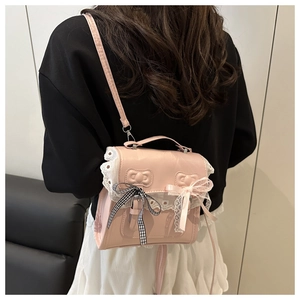 Detail of pink crossbody bag with white lace trim and black gingham bow accents