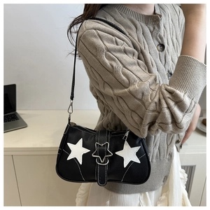 Detail of black pebbled leather shoulder bag with white star patches and metal star buckle