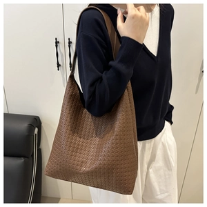 Λεπτομέρεια καφέ πλεκτής τσάντας tote με υφή Intrecciato και φαρδύ λουράκι ώμου