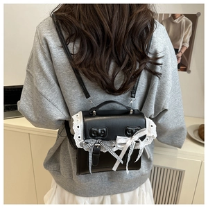 Detail of a black Lolita PU leather backpack with white lace and ribbons on a model