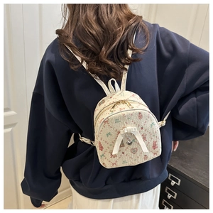 Close-up of cute cartoon mini backpack with silk bow and heart pendant detail
