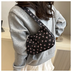 Detailed back view of a black underarm bag with pink bow embroidery on a female model