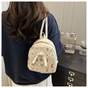 Detailed view of mini printed backpack with strawberry patterns and heart charm