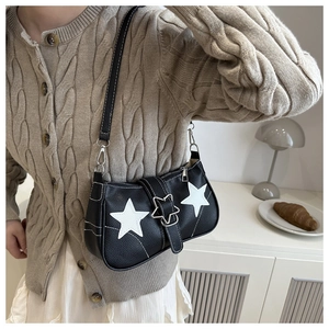 Detail of black lychee leather shoulder bag featuring two white stars and star-shaped metal buckle