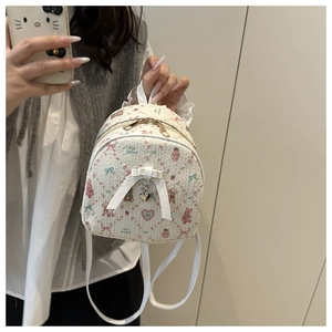 Mirror selfie showing a mini cream backpack with pink bow, bear and strawberry prints