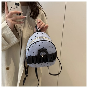 Close-up of mini striped backpack with black lace, bow detail, and heart pendant