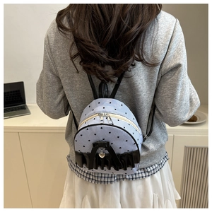 Détail d'un mini sac à dos bleu clair à motif cœurs avec nœud noir et pendentif cœur