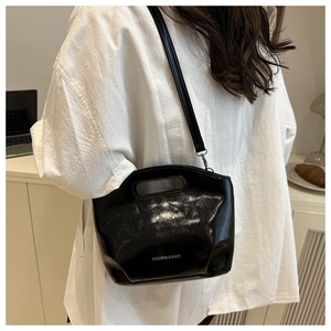 Detail of glossy black leather tote bag with white text and minimalist handle design