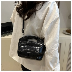Rear view of woman wearing a black patent leather chain handbag with shoulder strap