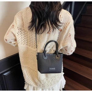 Back view of a mini black textured bucket bag with white fashion tag on wooden stairs