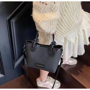Detail of black woven texture bag with FASHION label and decorative knot on handle