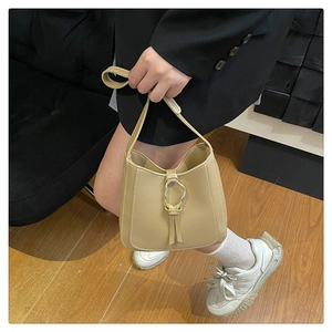 Detail of beige PU leather bucket bag featuring a decorative gold hardware buckle