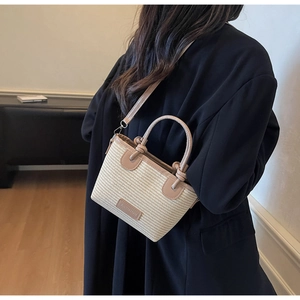 Detail of straw woven crossbody bag with brown leather trim and fashion patch