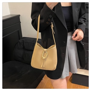 Detalle de bolso tipo cubo de cuero crema minimalista con hebilla de metal dorado y nudo