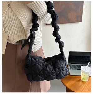 Detail of black quilted puffer bag with scrunchie strap shown in a casual lifestyle setting