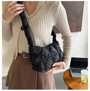 Close-up of black quilted puff shoulder bag with soft shoulder strap and pleated texture
