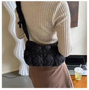 Sac bandoulière matelassé noir en nylon avec détail de nœud porté par un mannequin