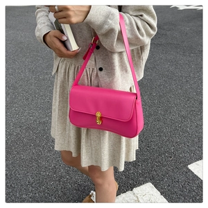 Fashionable bright pink underarm bag with gold metal buckle shown on a model