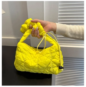 Detail of a bright yellow quilted puffer bag featuring a pleated handle and drawstring