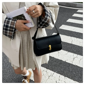 Detail shot of the gold rectangular lock on a black minimalist underarm bag for women