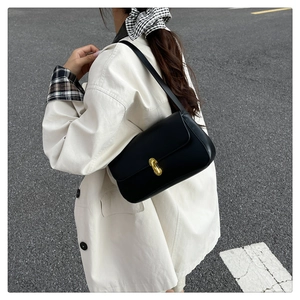 Detailed close-up of a black minimalist underarm bag with a golden metal twist lock