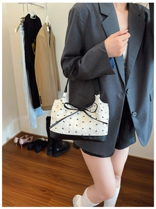 Detail showing white jacquard underarm bag with black bow tie print and leather strap