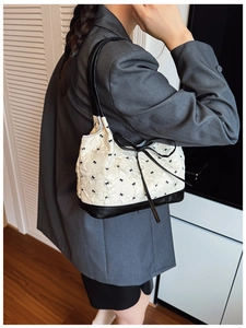 Detail of white textured fabric bag with black bow embroidery and slim shoulder strap