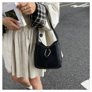 Détail du sac seau en cuir noir avec coutures blanches et boucle en anneau doré