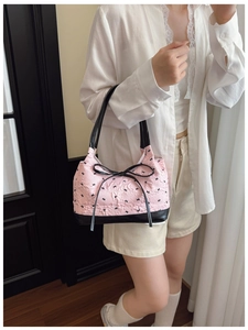Pink bubble textured handbag with black ribbon bow detail and leather trim shown with a model