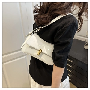 Detail of white patent leather shoulder bag featuring a sleek golden oval twist lock clasp