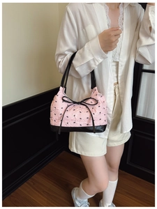 Detailed view of pink bow-patterned handbag carried by a model in a casual setting