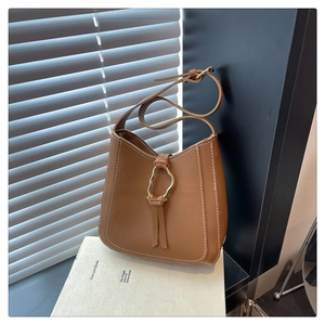 Detailed view of caramel leather shoulder bag with white contrast stitching and gold ring