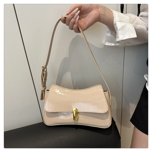 Detail of glossy beige patent leather bag with a luxury gold metal lock clasp